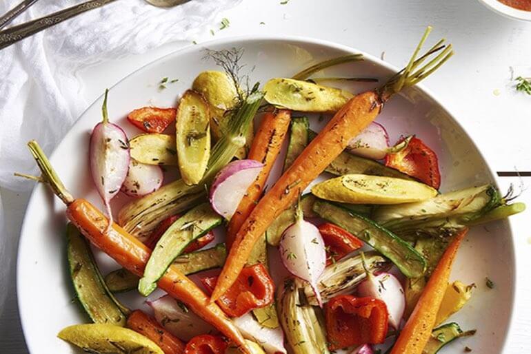 Roasted tomato vinaigrette recipe served with roasted vegetables on a white plate.