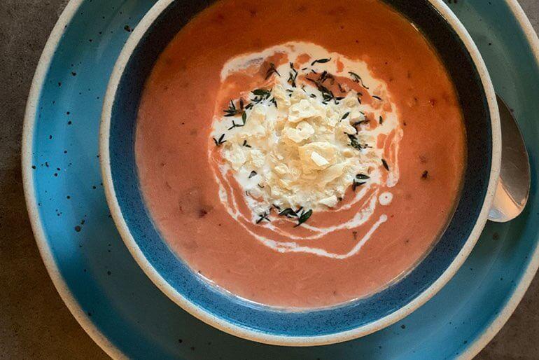 Manhattan clam chowder soup recipe in a teal coloured bowl garnished with fresh thyme and cream.
