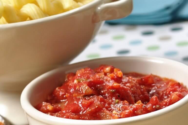Classic marinara sauce recipe with organic crushed tomatoes and basil served in a small sauce bowl next to cooked pasta.