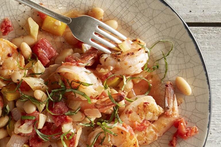 Shrimp and white bean provencal recipe with diced tomatoes and extra large shrimp served on a white plate.