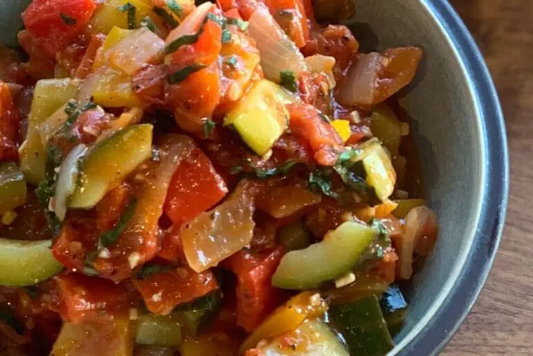 Recette de ratatouille au basilic et à la tomate concassée, avec des courgettes, des poivrons et de l'ail hachés.