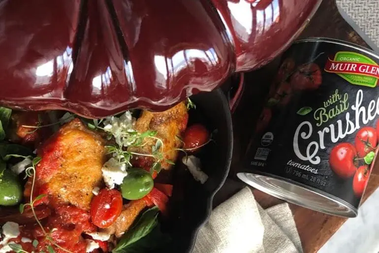 Recette de cuisses de poulet braisées dans une sauce tomate avec des olives vertes et de la feta de chèvre émiettée.