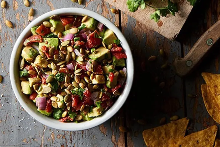 Avocado salsa recipe in a bowl served with a side of tortilla chips.