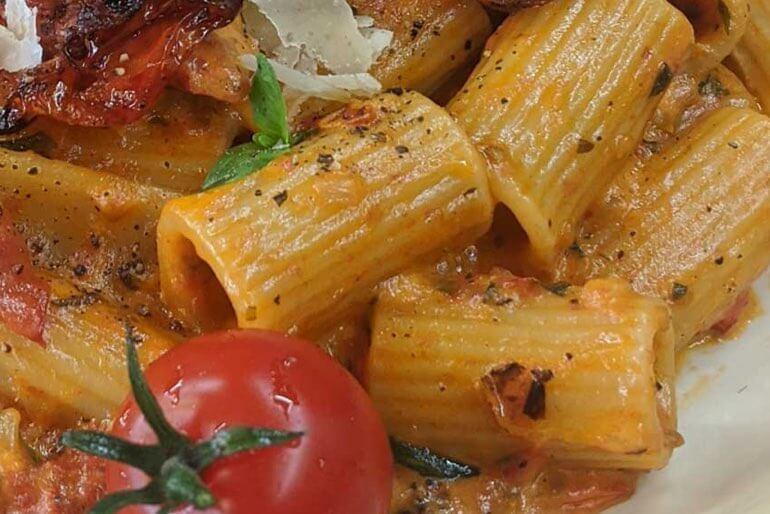 Rigatoni basil and rose recipe topped with a cherry tomato and basil leaves.